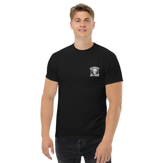 Male model wearing black T-shirt — front left chest small alien head graphic with floral frame