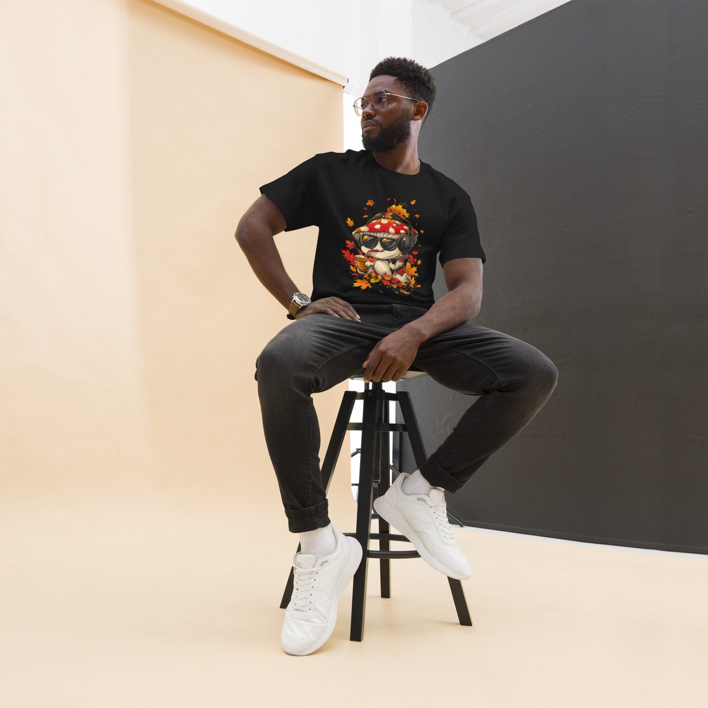 Male model seated, wearing a black t-shirt with fall-themed mushroom design.