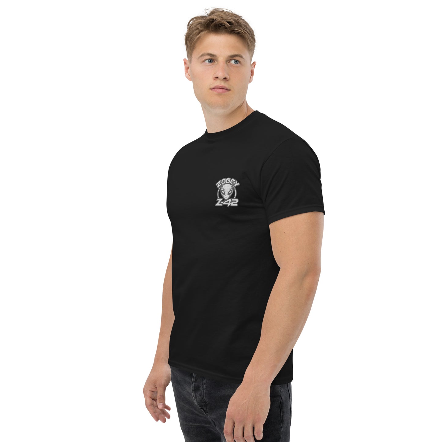 Male model wearing black T-shirt — front left chest small alien head graphic with frame