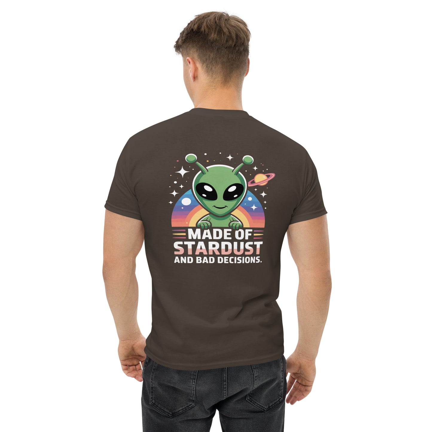 Male model wearing brown T-shirt — back print: green alien with planets and text MADE OF STARDUST AND BAD DECISIONS