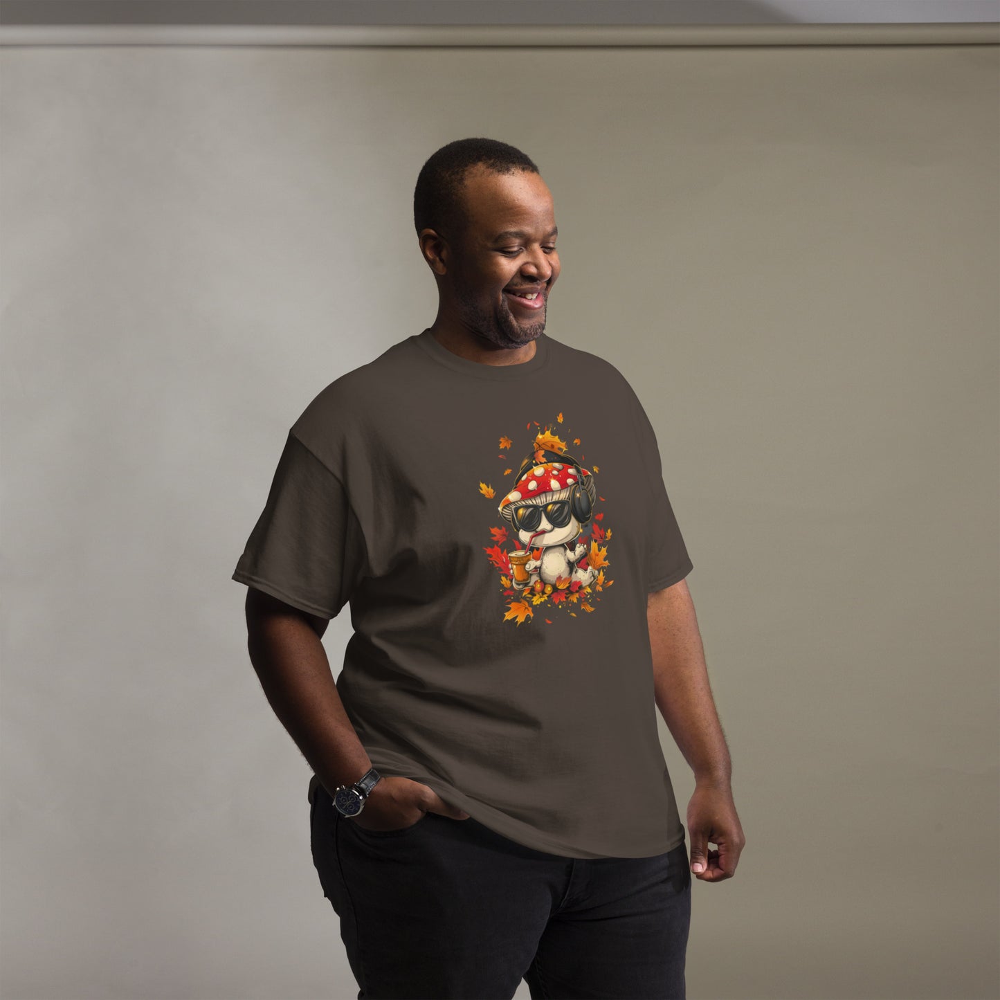 Male model in a dark brown t-shirt featuring cartoon mushroom surrounded by autumn foliage.