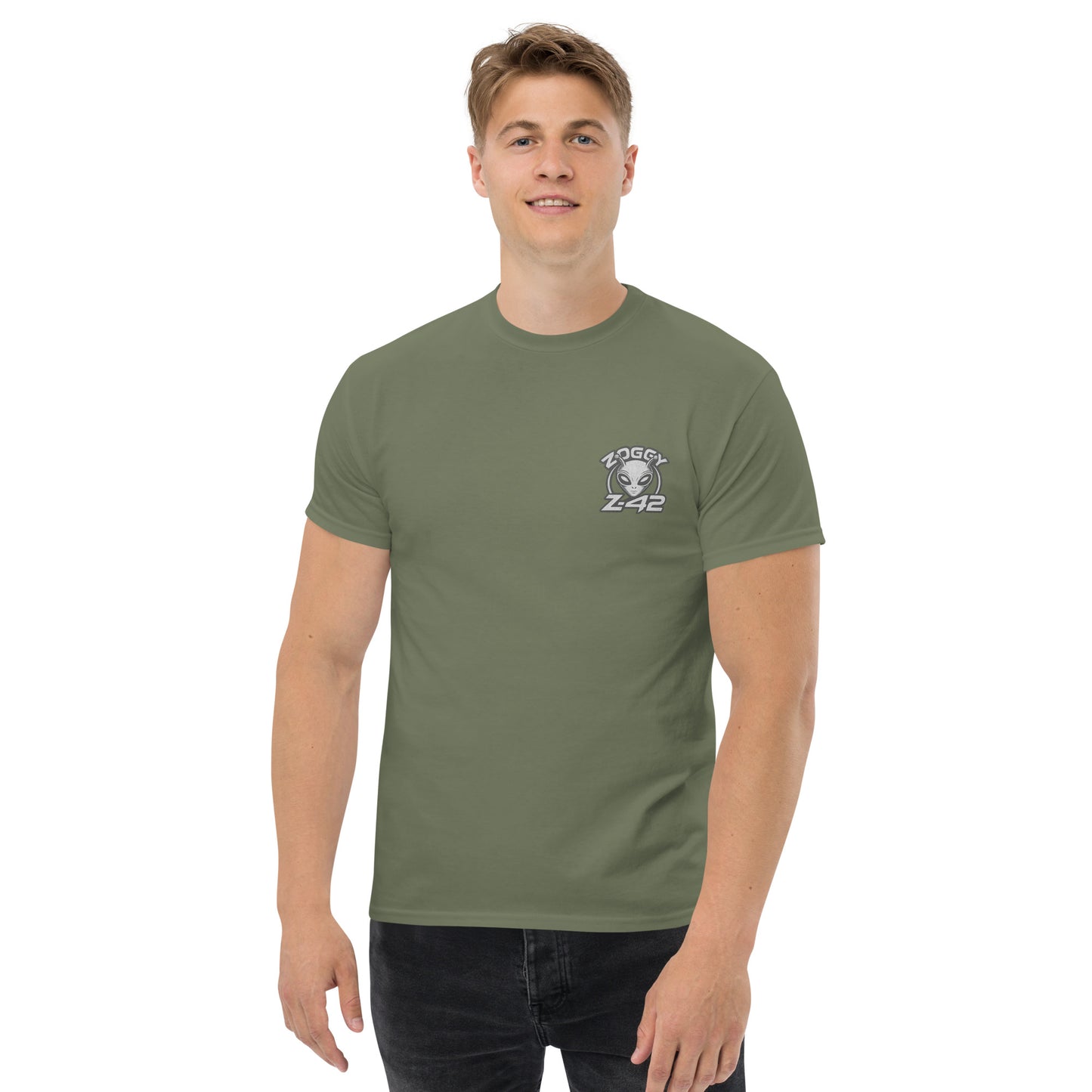 Male model wearing olive green T-shirt — front left chest small alien head graphic with floral frame