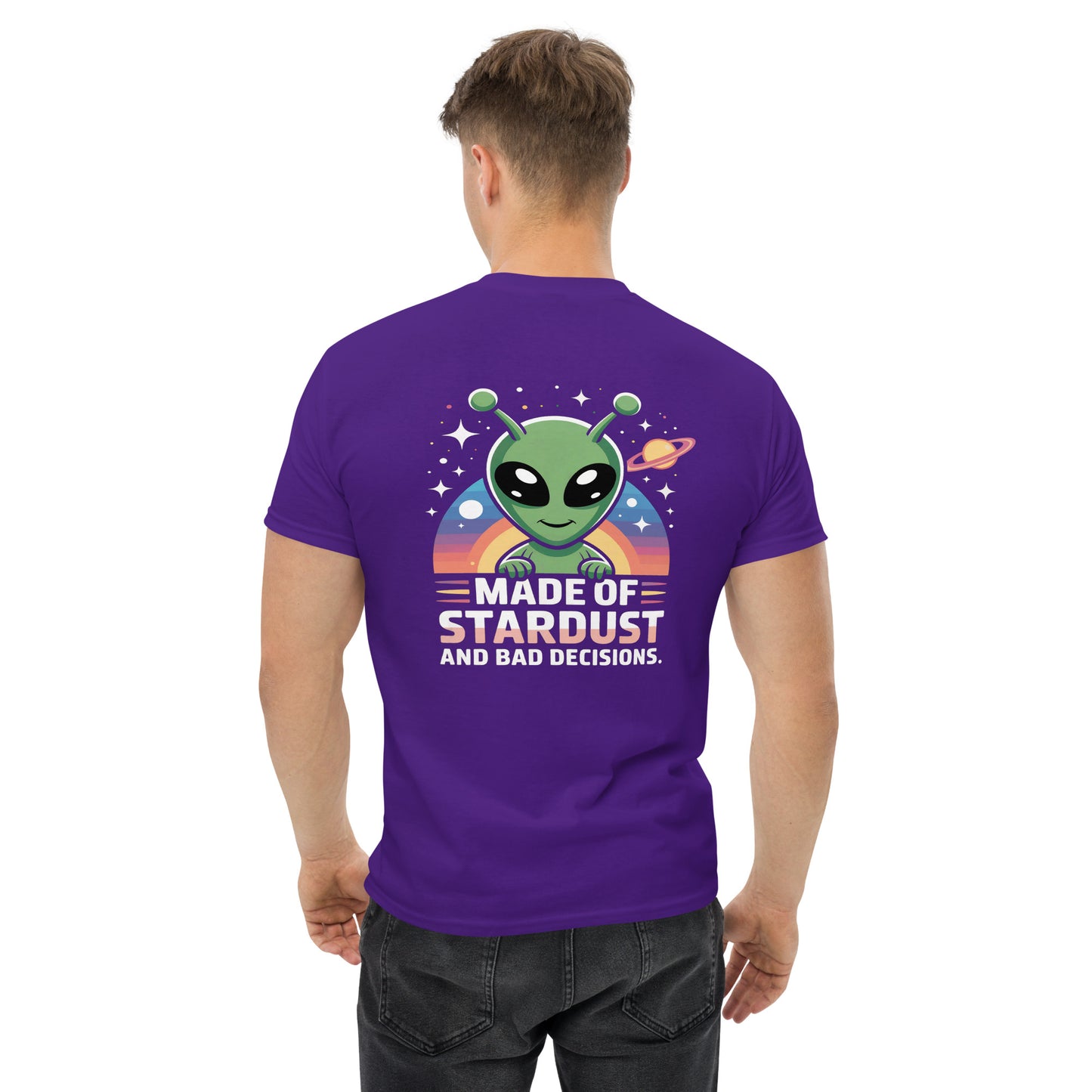Male model wearing purple T-shirt — back print: green alien with planets and text MADE OF STARDUST AND BAD DECISIONS