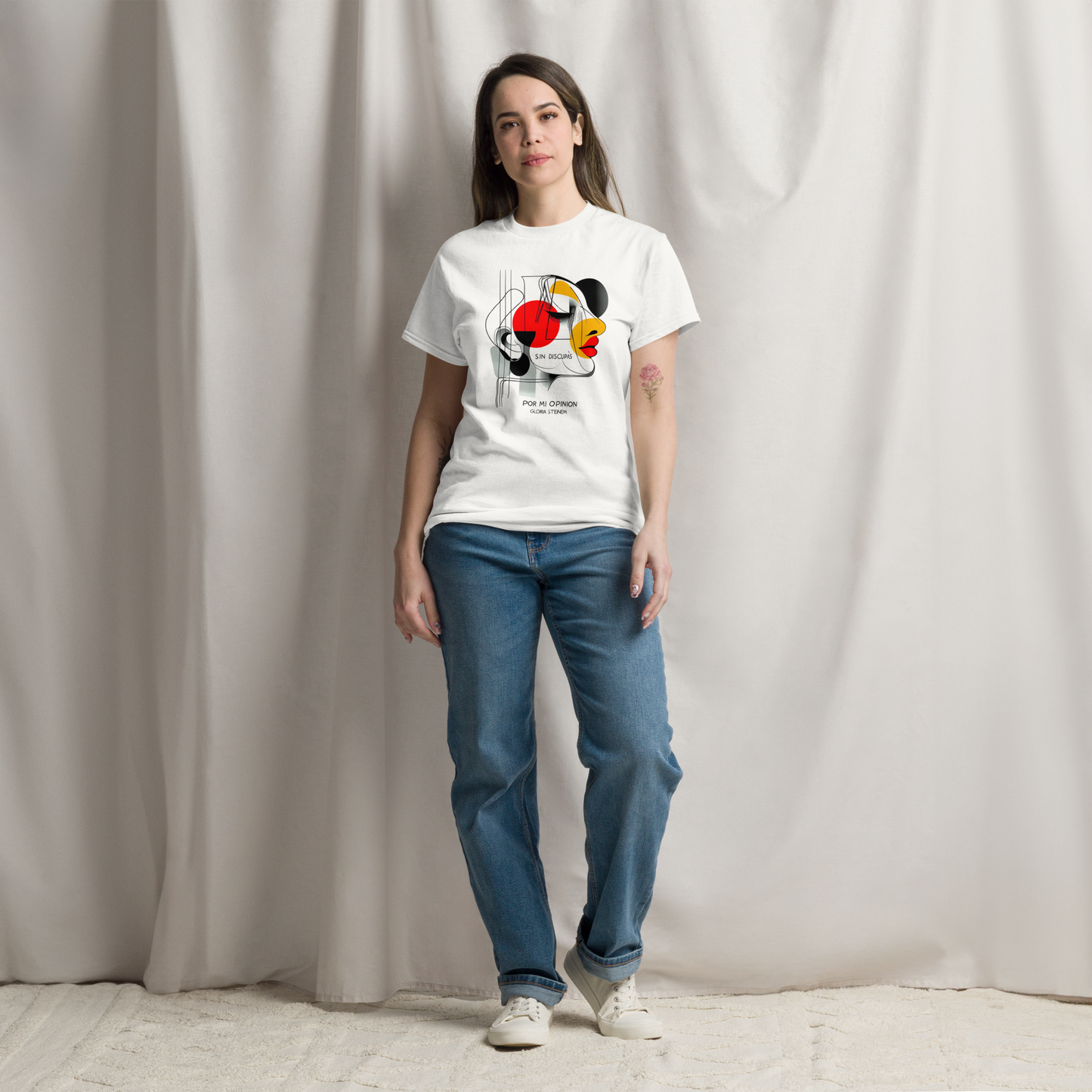 Model wearing the white T-shirt with the phrase clearly displayed with the abstract face design and slogan “No me disculpo por mi opinión.”