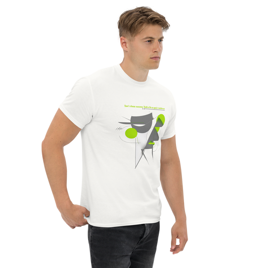 Male model wearing white T-shirt — front print: abstract geometric figure with green circles, text “be yourself, everyone else is already taken.”