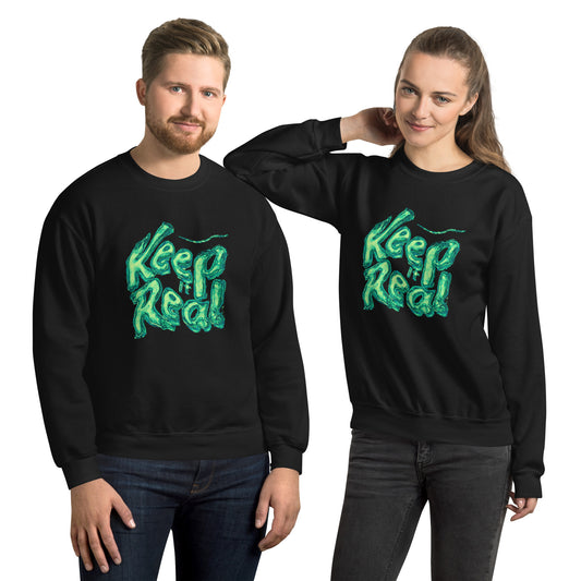 Man and woman wearing matching black sweatshirts with “Keep Real” green graphic.