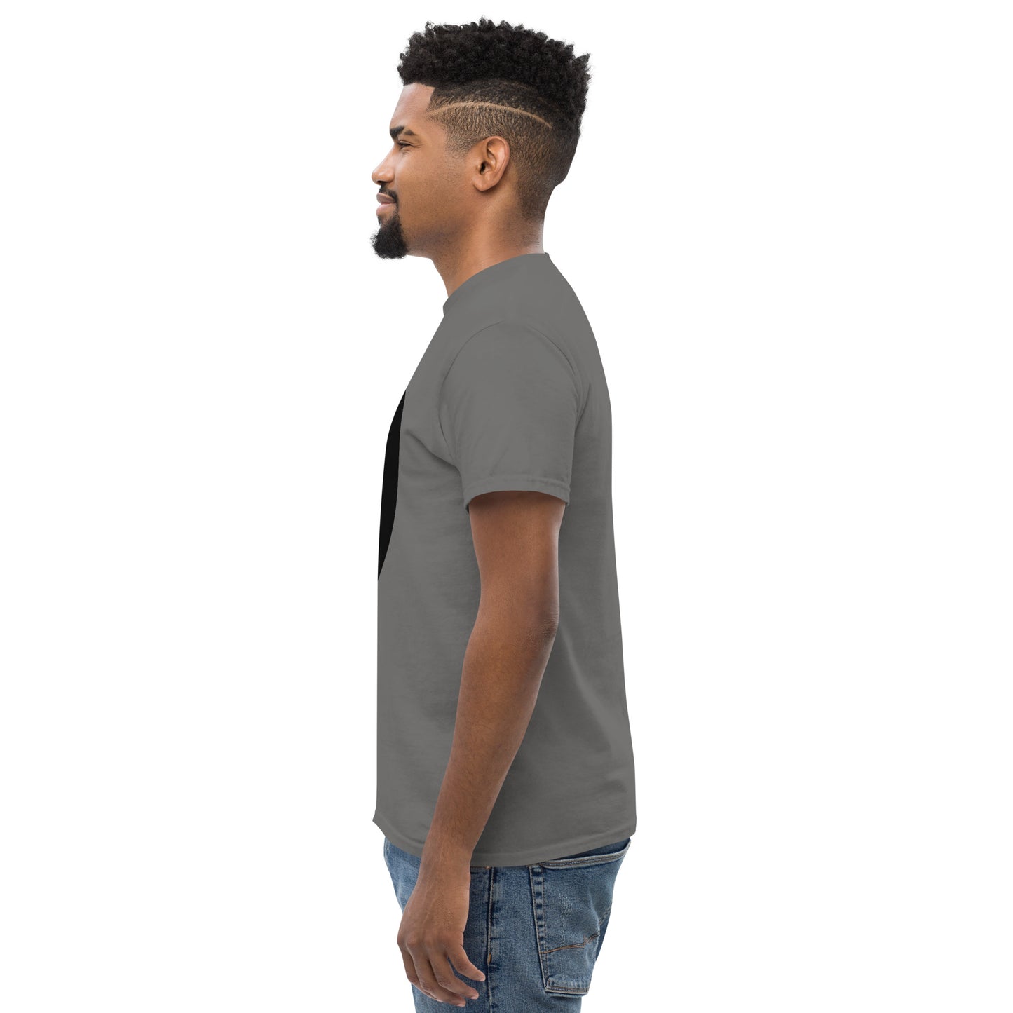 Side view of the t-shirt worn by a model, showing the clean silhouette and relaxed fit. The right sleeve mark is partially visible, positioned low on the sleeve as a discreet signature element.