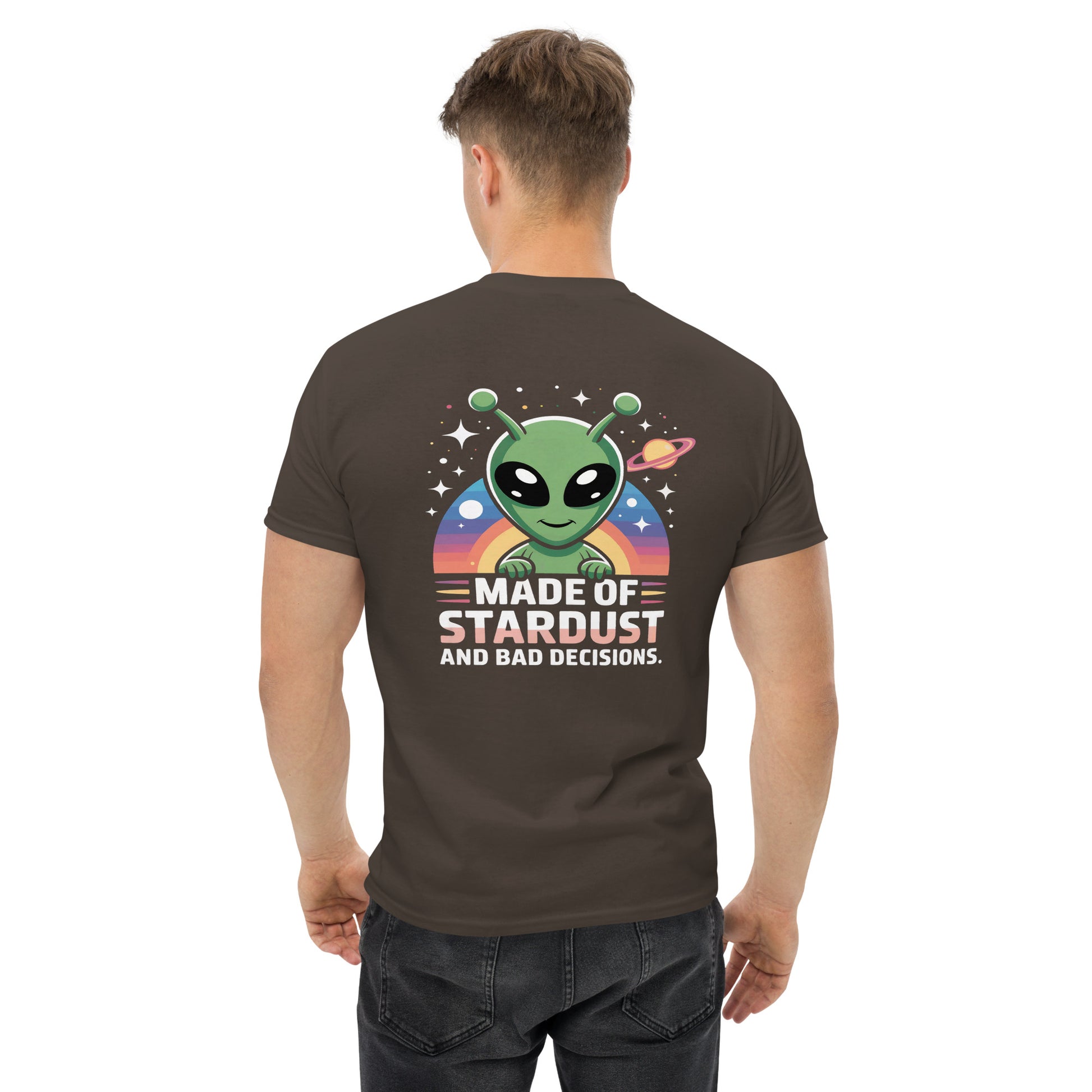 Male model wearing brown T-shirt — back print: green alien with planets and text MADE OF STARDUST AND BAD DECISIONS