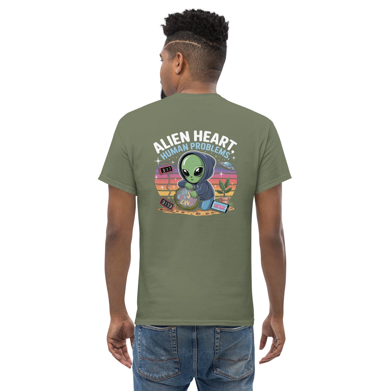 Male model wearing olive green T-shirt — back print: green alien in floral frame with text ALIEN HEART