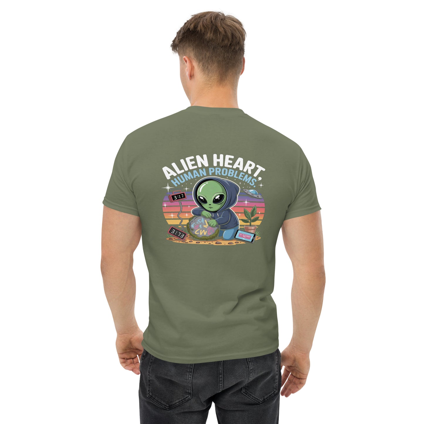 Male model wearing olive green T-shirt — back print: green alien in floral frame with text ALIEN HEART