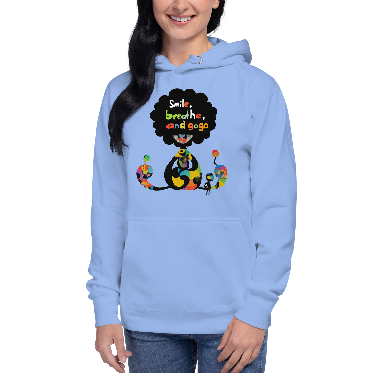 Woman wearing a light blue unisex hoodie featuring a colorful Smile, Breathe, Repeat illustration with kawaii-inspired characters and vibrant graphic details.