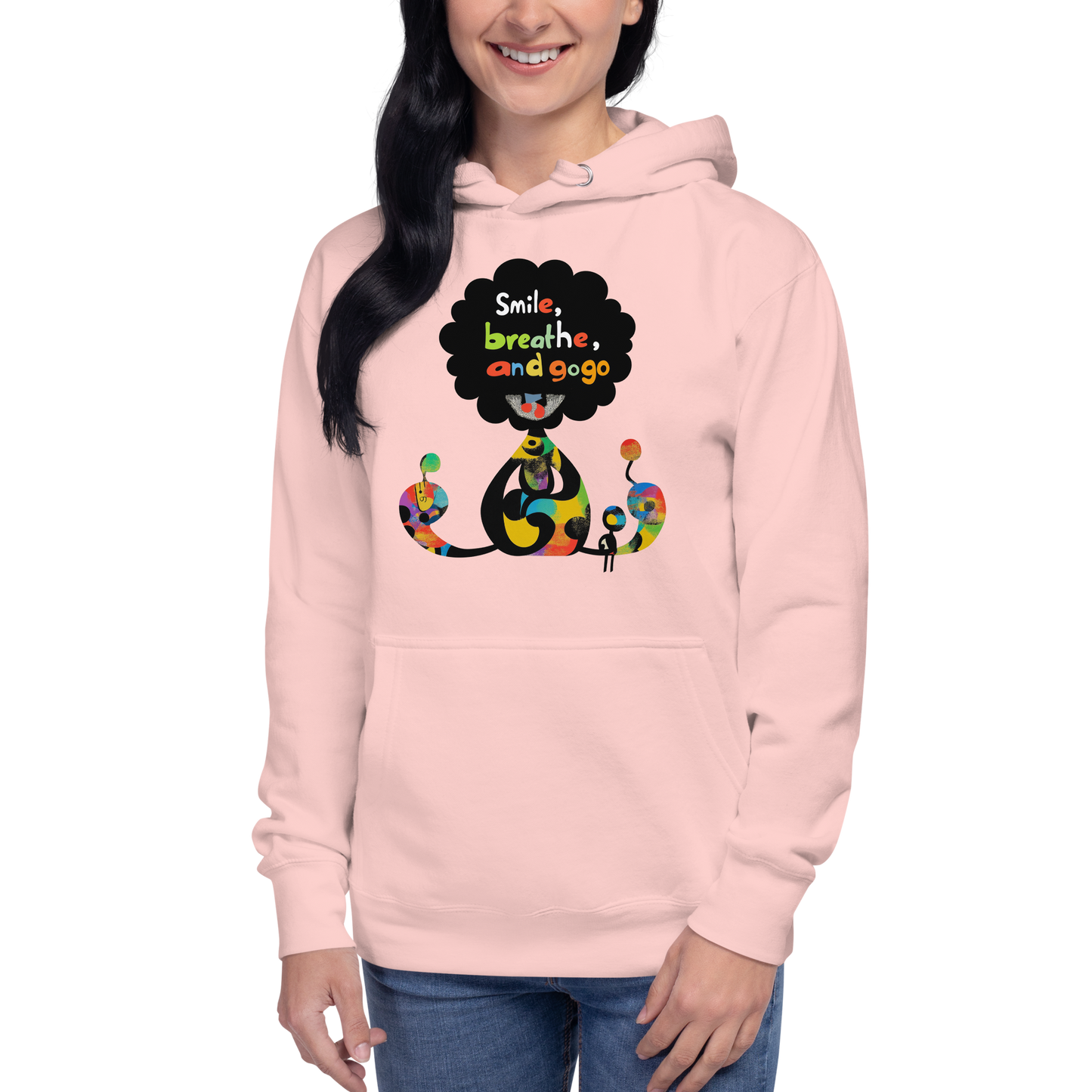Woman wearing a pink unisex hoodie featuring a playful Japanese-inspired graphic with colorful characters, whimsical elements, and the phrase “Smile, Breathe, Repeat” in a cheerful pop art style.